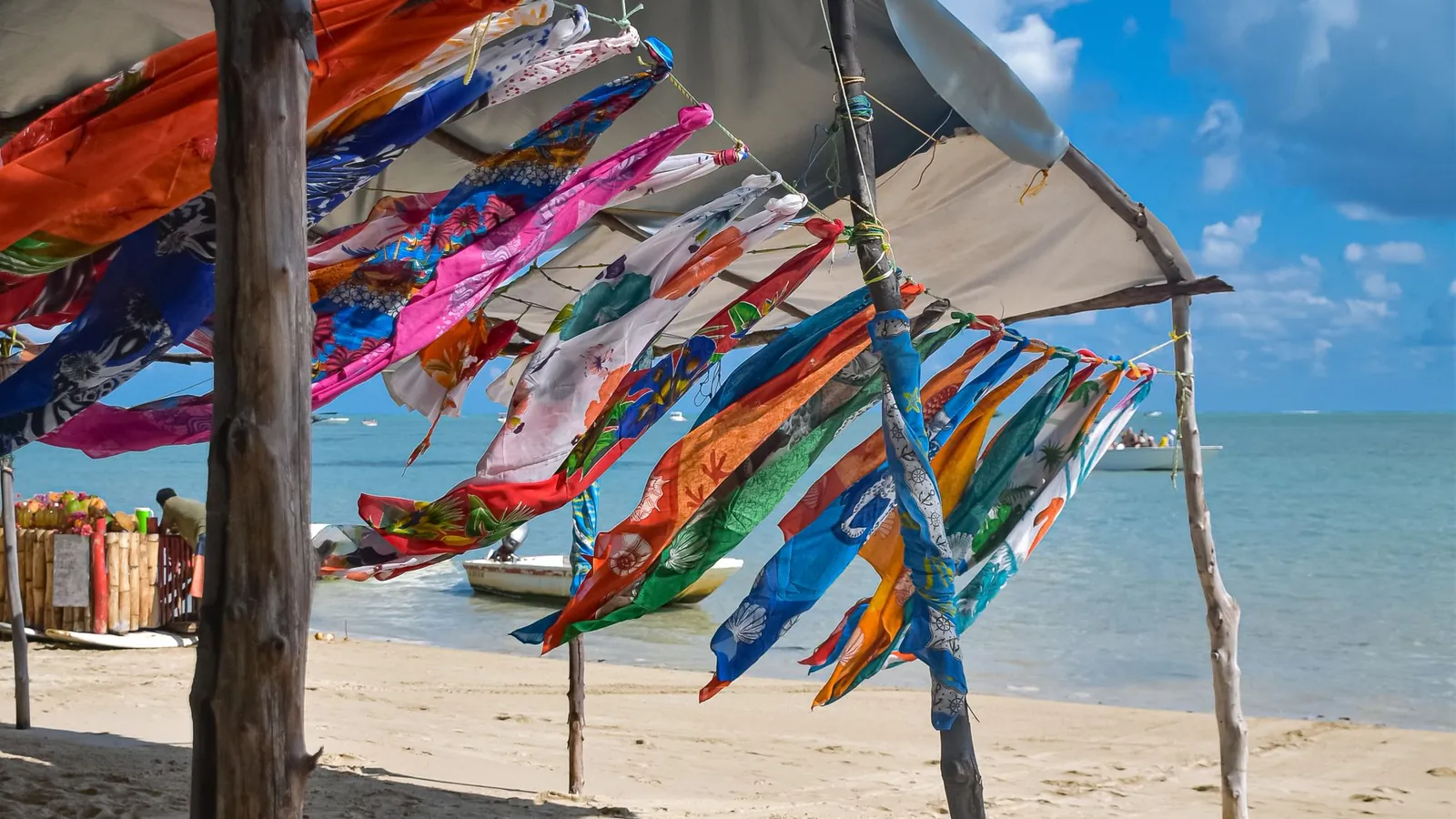 Colourful scarves hanging on a line under beach shelters