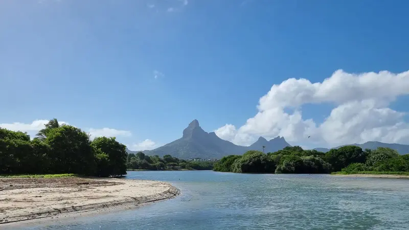 Lagune und Sandstrand mit einem spitzen Berg im Hintergrund
