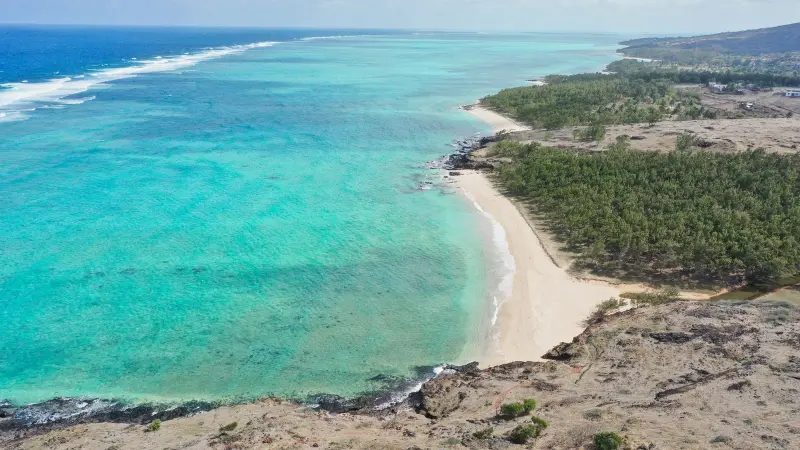 Luftaufnahme eines geschwungenen Strandes an einer türkisfarbenen Lagune