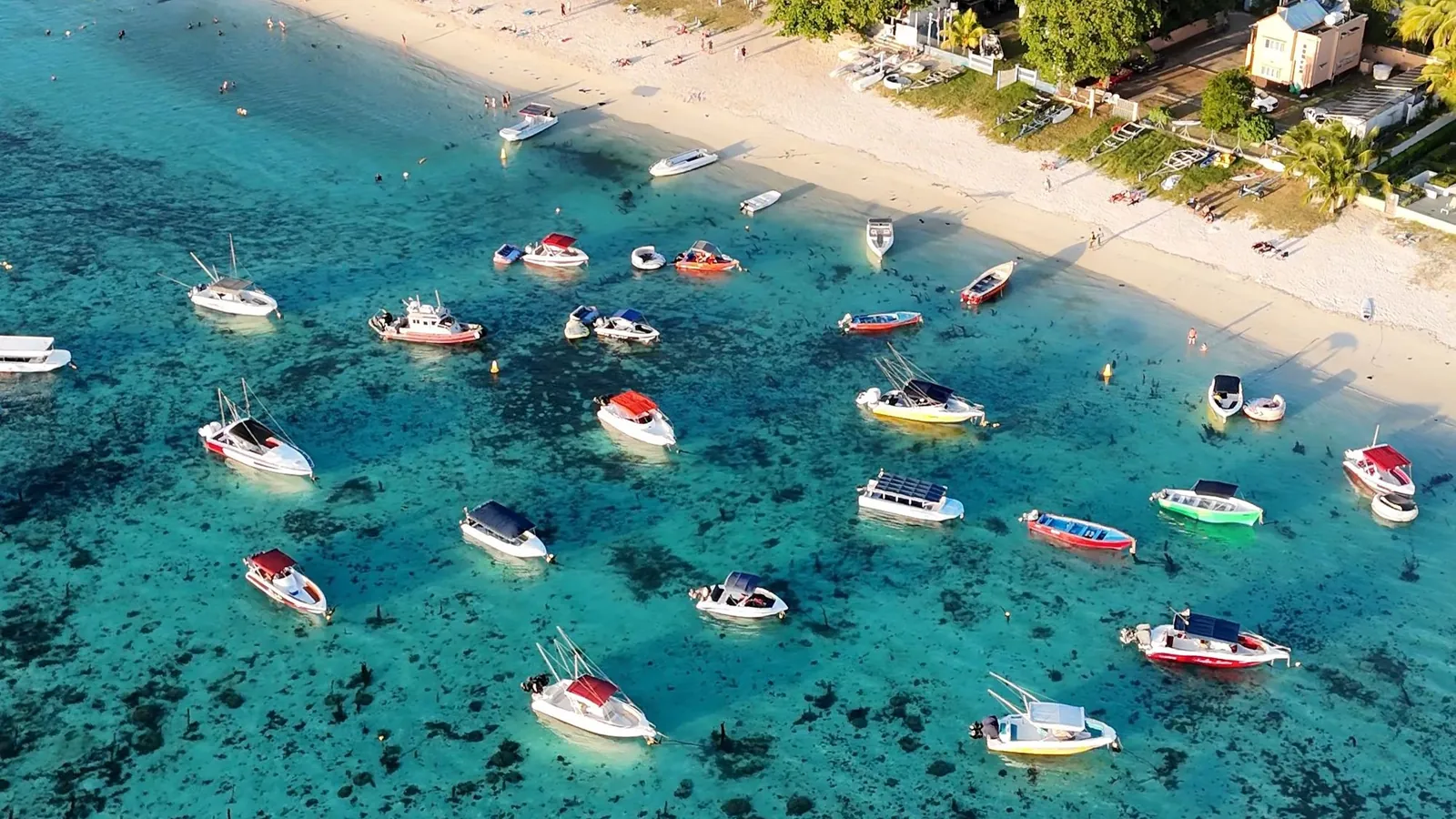 Aerial view of boats in a turquoise lagoon off a beach in Mauritius