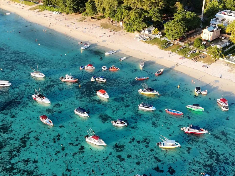 Luftaufnahme von Booten in einer türkisfarbenen Lagune vor einem Strand auf Mauritius